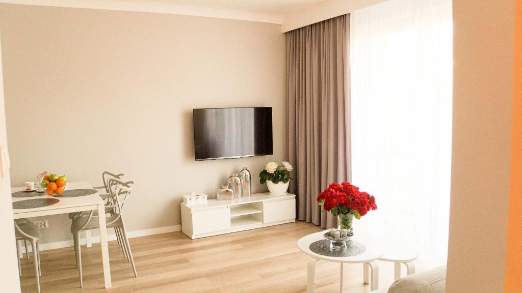 a living room with a table and a tv on the wall at Apartament Olimp in Gorzów Wielkopolski