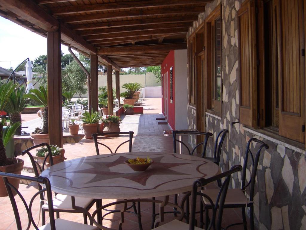 une terrasse couverte avec une table et des chaises. dans l'établissement L'Oasi di Ambra Dependance, à Ardea