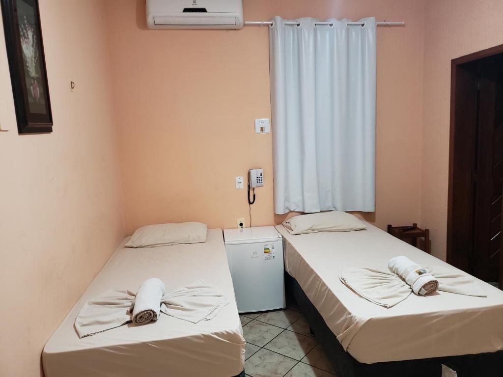 two beds in a room with a window at Hotel Transbrasil in Belém