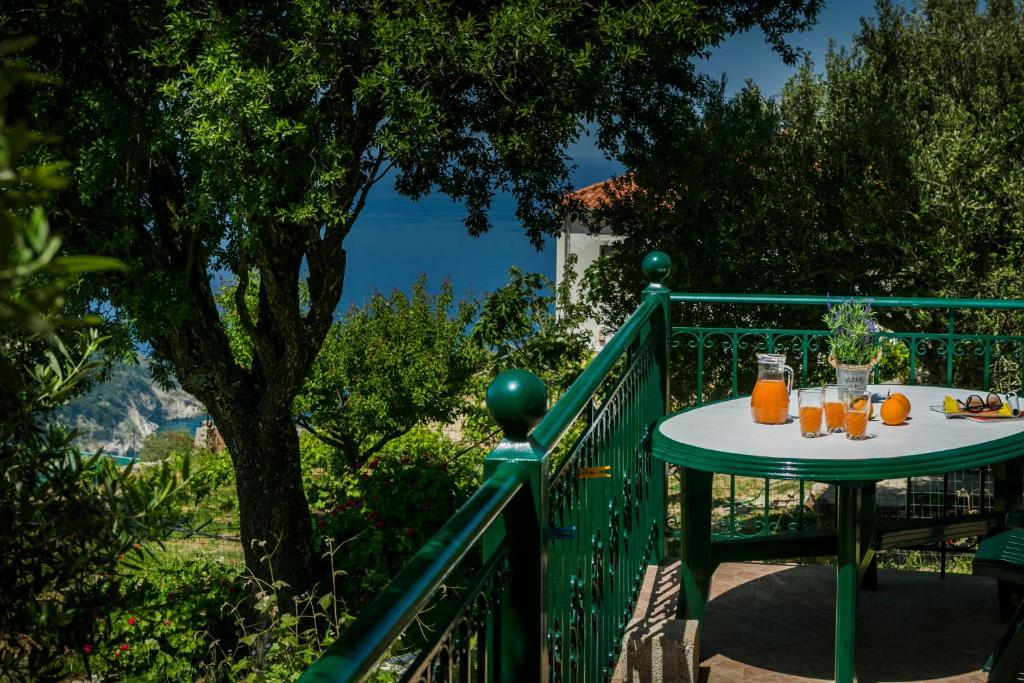 Apartment Voula Myrtos في Anomeriá: طاولة على شرفة مع عصير البرتقال عليها