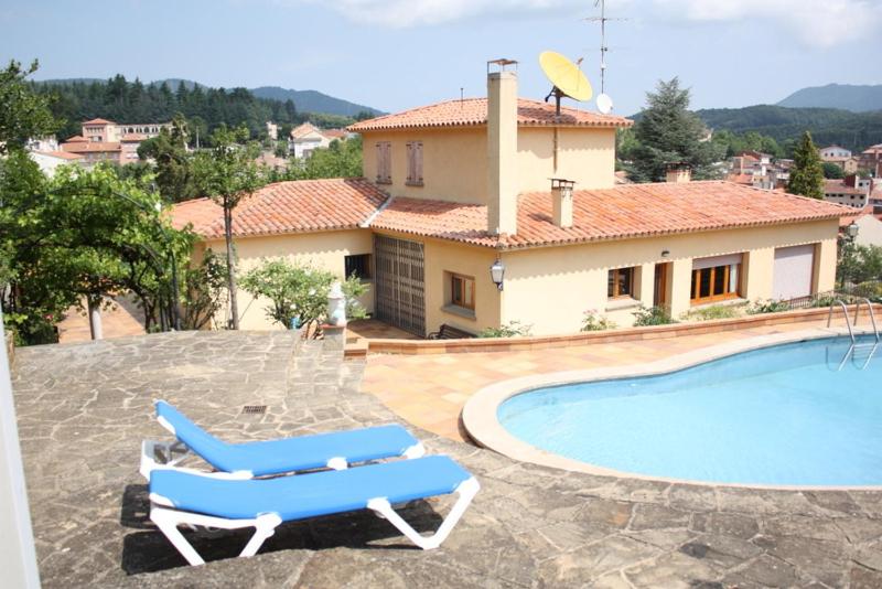 a house with a swimming pool and two blue lounge chairs at Torre Can Ripoll in Sant Hilari Sacalm