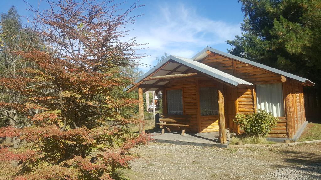 a wooden cabin with a bench in front of it at Complejo La Cautiva in Esquel