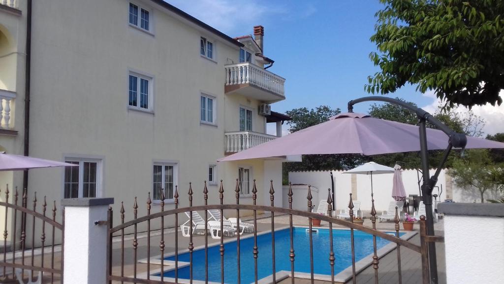 una piscina frente a un edificio con sombrilla en House apartments Ariamare, en Poreč