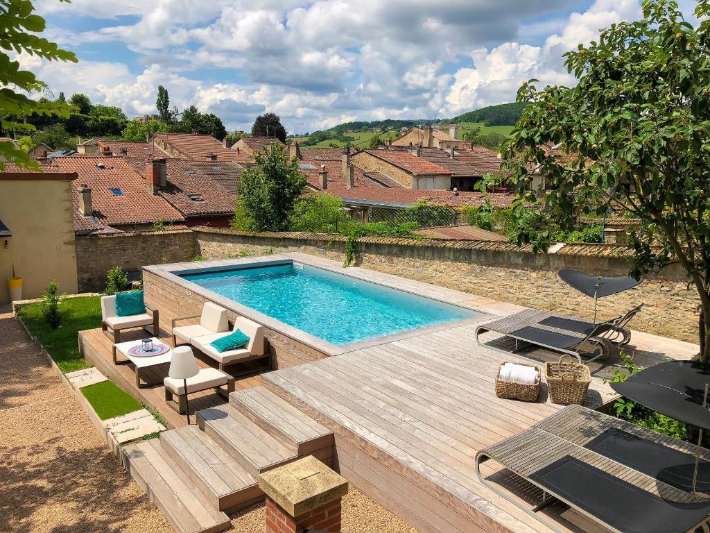 a swimming pool in a yard with a wooden deck at Maison TANDEM in Cluny