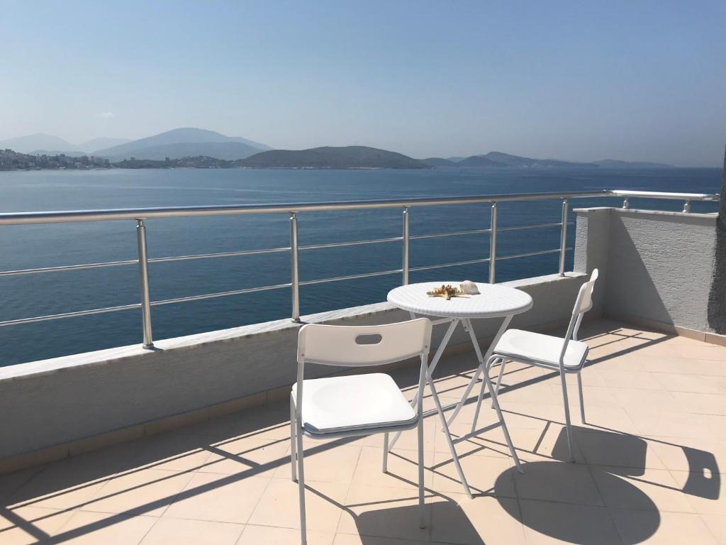 a table and chairs on a balcony with a view of the water at Kristina Bellavista Rooms in Sarandë