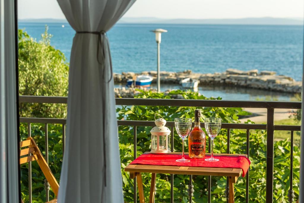 einen Tisch mit Weingläsern auf einem Balkon mit Meerblick in der Unterkunft Apartment Veve in Privlaka
