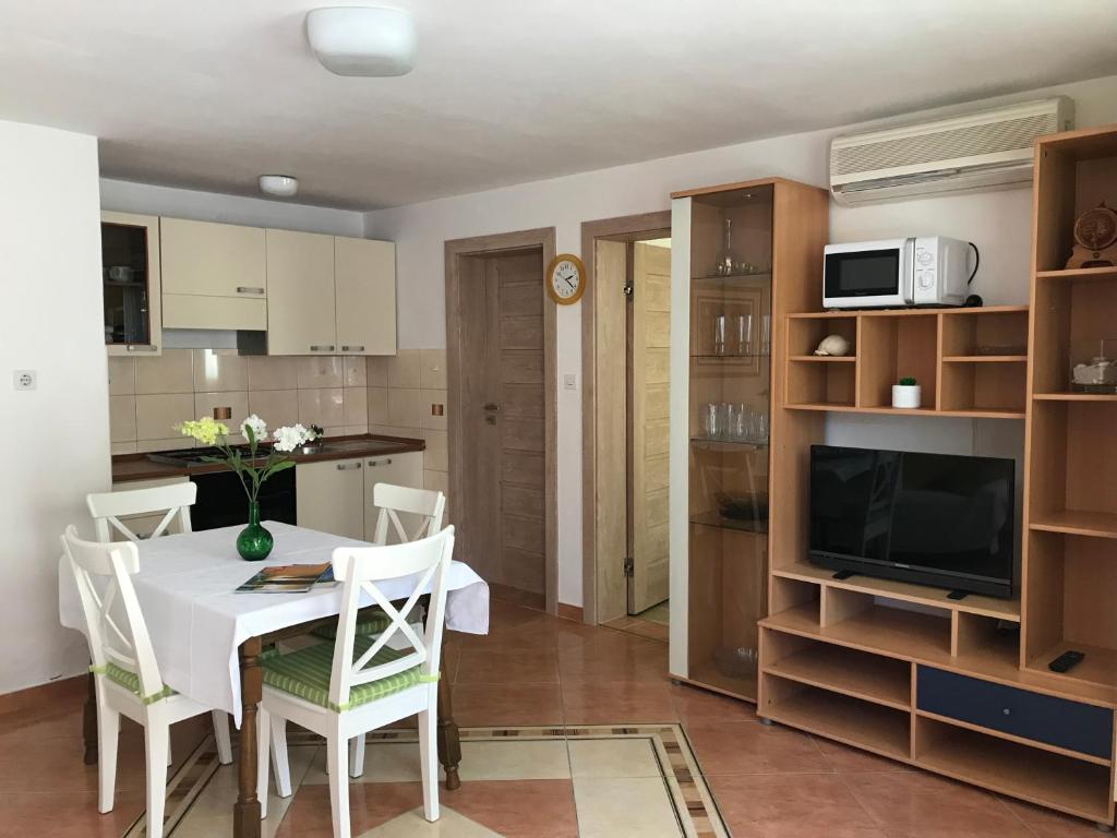 kuchnia i jadalnia z białym stołem i krzesłami w obiekcie Apartments Biskup w mieście Privlaka