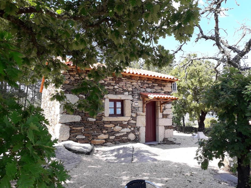 a stone house with a red door in a yard at Casa do Feitor - Douro - Quinta da Cabrida in Sendim