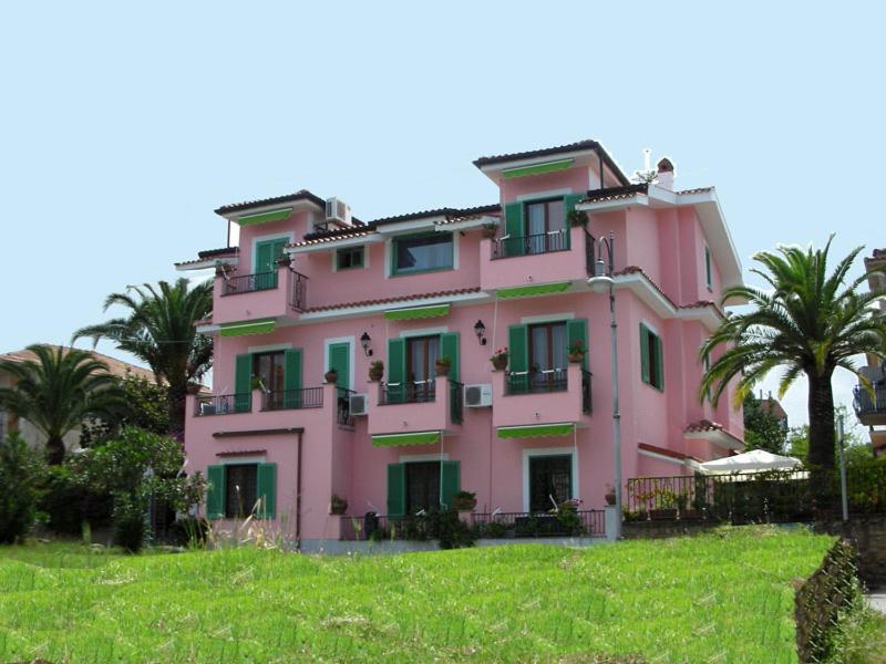 une maison rose avec des palmiers devant elle dans l'établissement L'Elisea Maison De Charme, à Castellabate