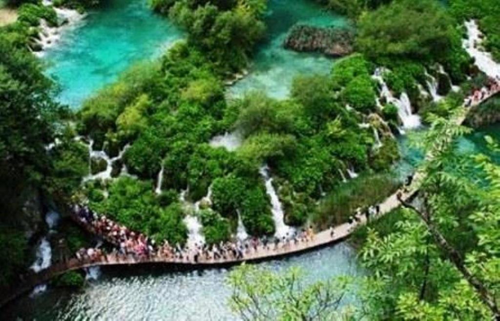 a large group of people walking across a river at Plitvice Valley Apartments in Ličko Petrovo Selo
