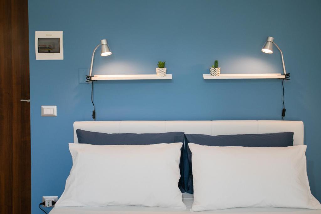 een blauwe muur met twee lampen boven een bed met kussens bij Isola Blu in Siracusa