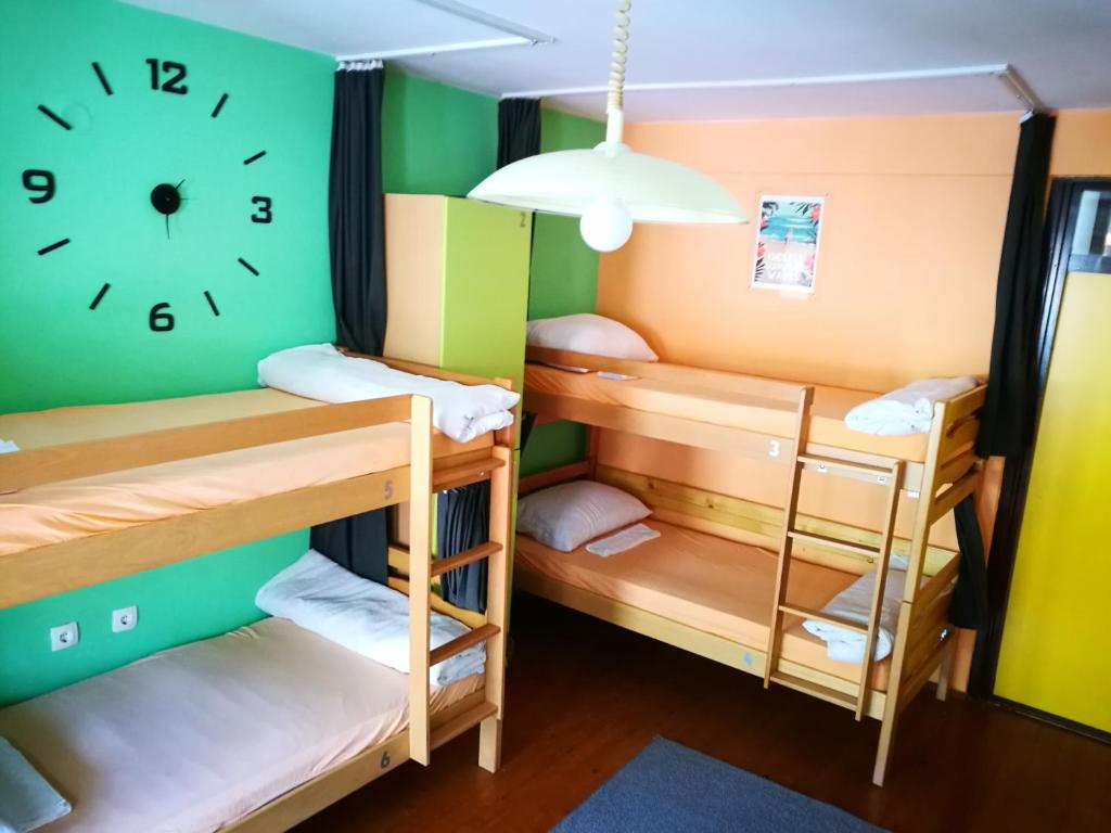 a room with bunk beds and a clock on the wall at Balkaneros Hostel in Mostar