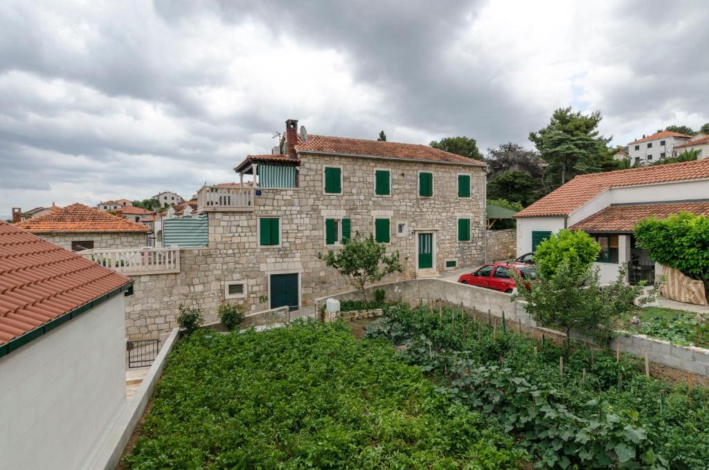 a large stone house with green windows in a yard at Apartments Jurica in Postira