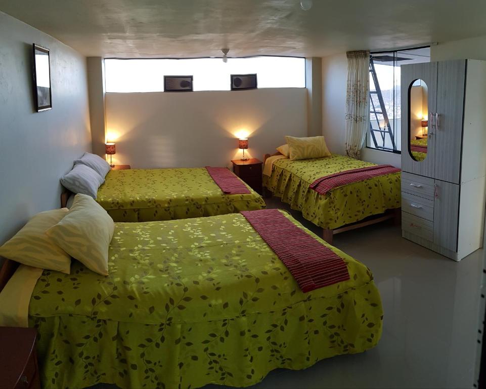 a hotel room with two beds with yellow sheets at Feliz Vista Casa-Hospedaje in Cusco