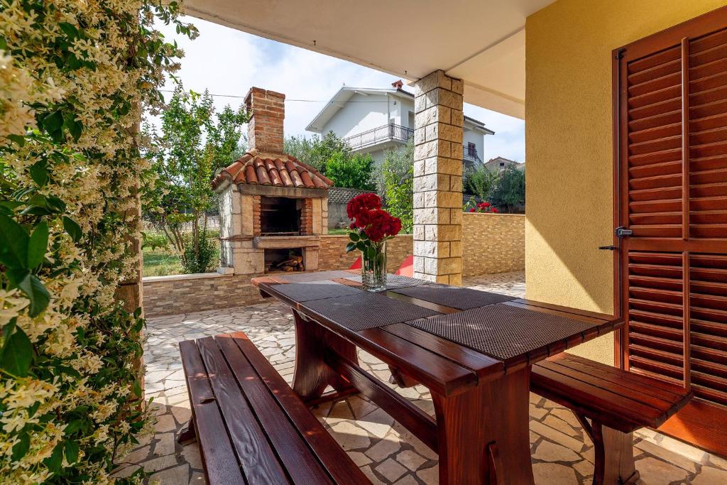 una mesa de madera y un banco en un patio con chimenea en Guest House Ravnić, en Poreč