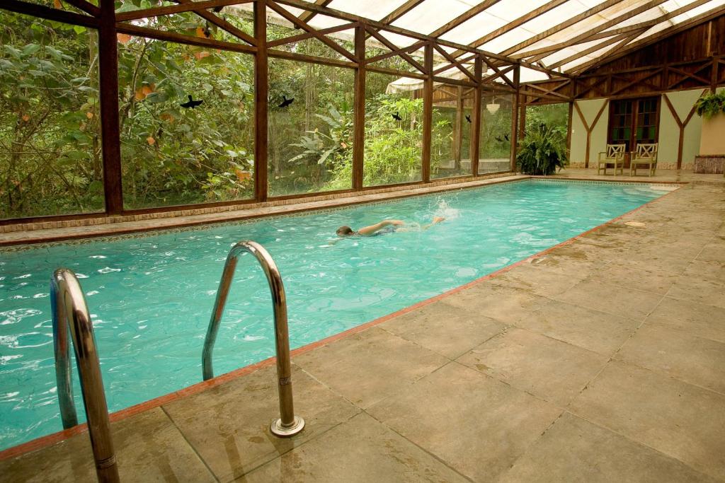 a person swimming in a swimming pool with an open structure at Sachatamia Lodge in Mindo