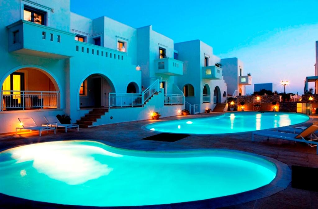 a swimming pool in front of a house at night at Mitos Suites in Agios Prokopios