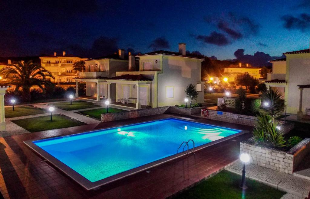 a swimming pool in front of a house at night at Praia Del Rey Pool View ByThe Sea in Casal da Lagoa Seca