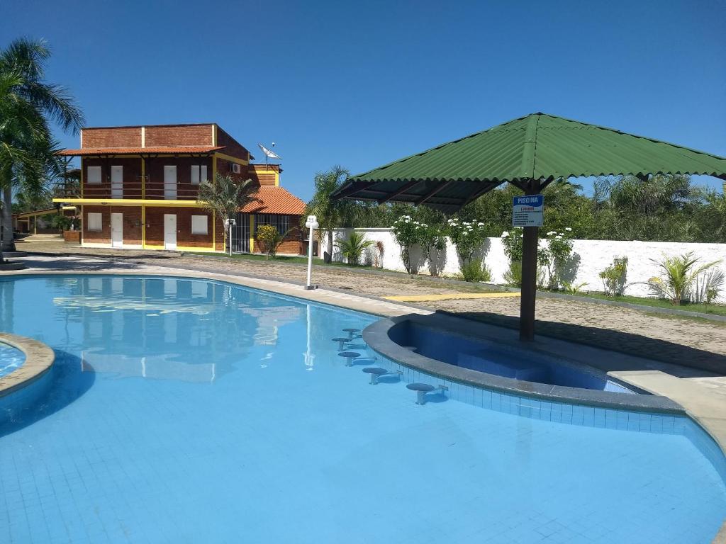 a large swimming pool with an umbrella in front of a house at Porto dos Lencóis - Chalé Tipo Apartamento in Barreirinhas