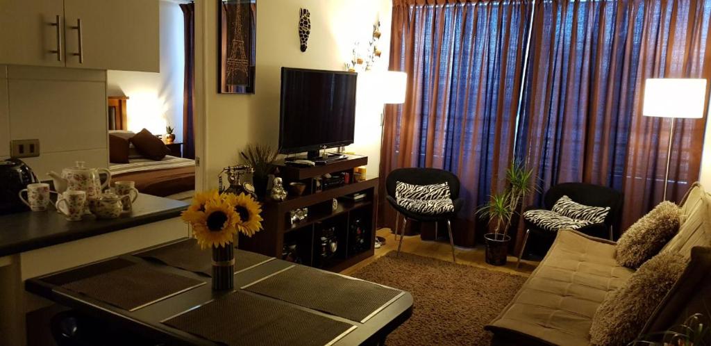 uma sala de estar com um sofá e uma mesa com uma televisão em Eco Alameda em Santiago