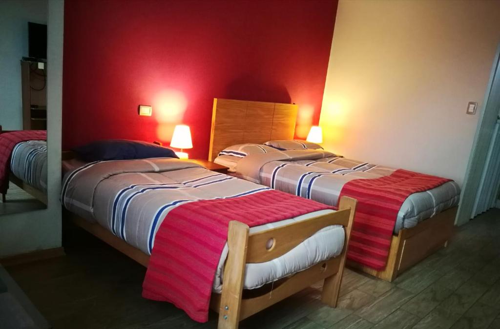 2 Betten in einem Zimmer mit roten Wänden in der Unterkunft Habitaciones en Buena Vista in Lima