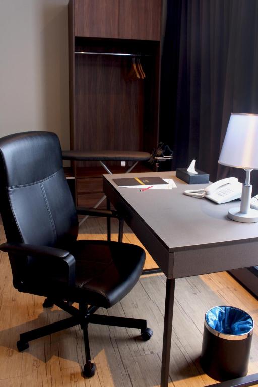 A dedicated hotel work area with a desk, leather office chair, telephone and wardrobe.