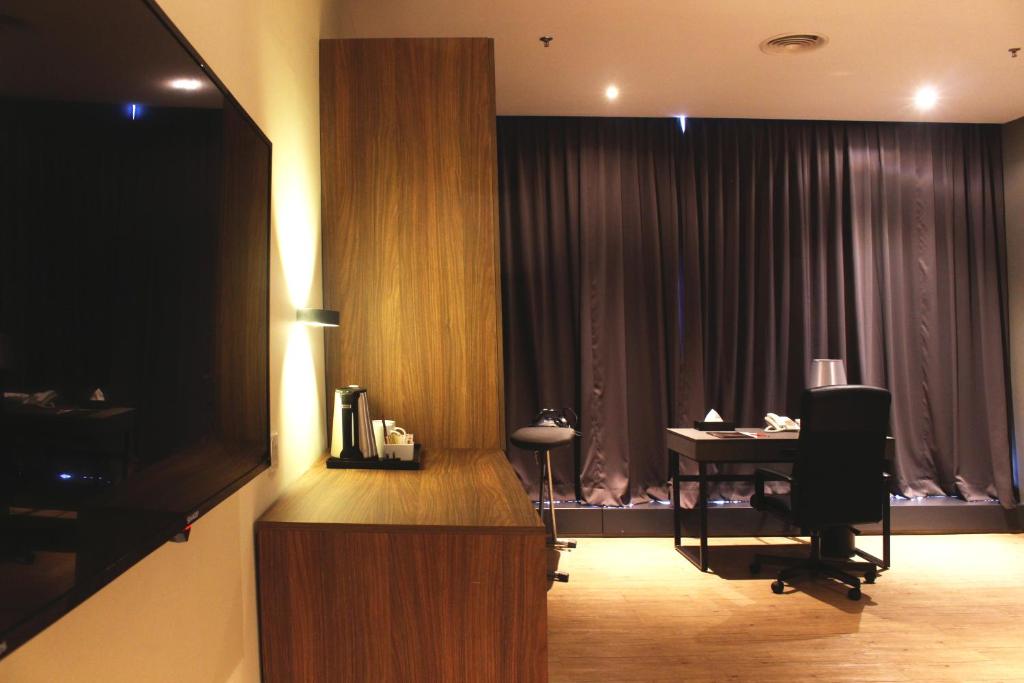 A hotel work area with a desk, office chair, television and beverage station.