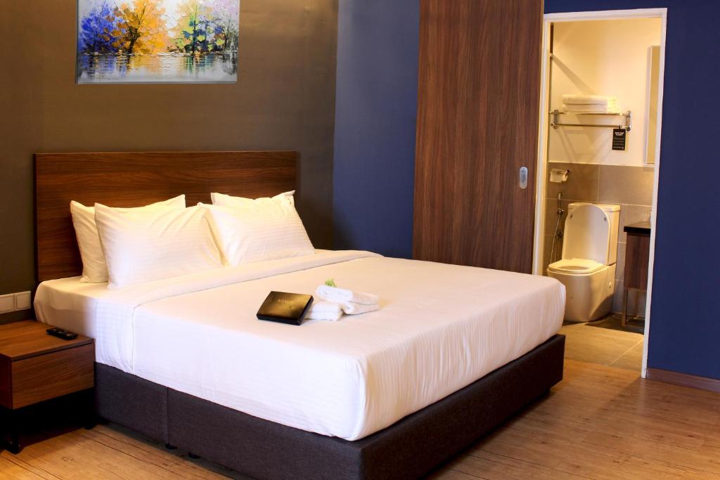 A made bed with a bedside table and open bathroom doorway.