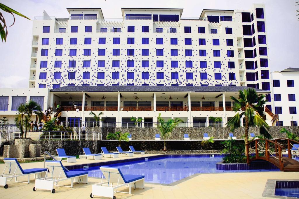 a hotel with chairs and a pool in front of a building at Best Western Plus Atlantic Hotel in Sekondi-Takoradi