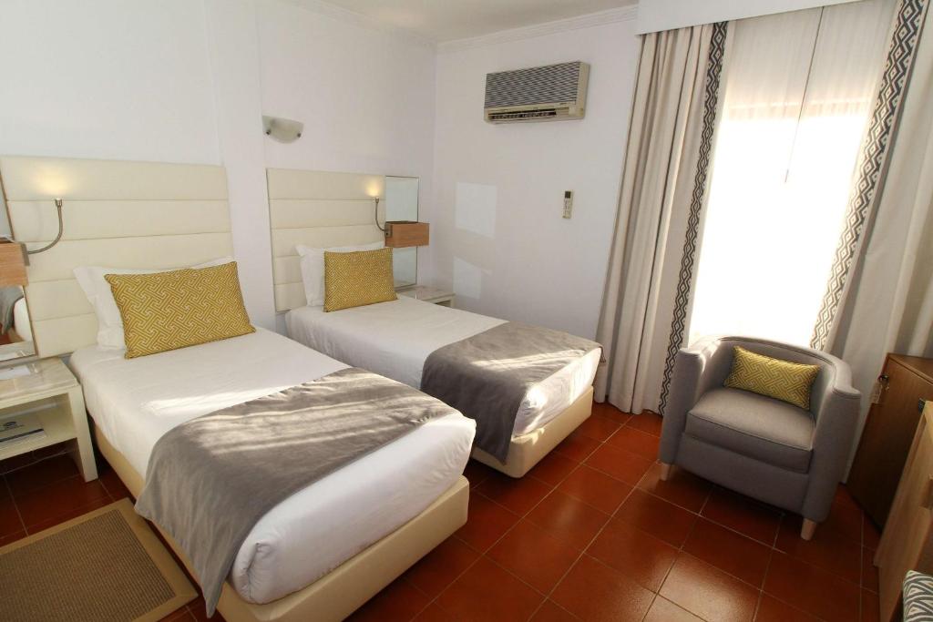 a hotel room with two beds and a chair at Best Western Hotel Dom Bernardo in Faro