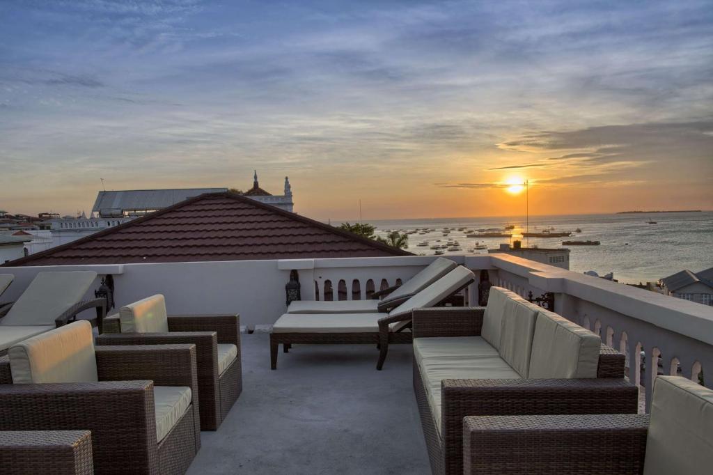 a balcony with chairs and a sunset on the ocean at BW Plus Zanzibar in Zanzibar City