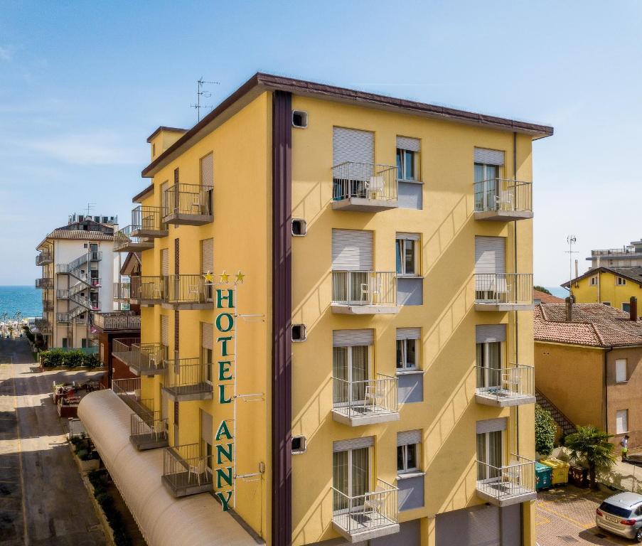 un edificio amarillo con un cartel. en Hotel Anny en Lido di Jesolo