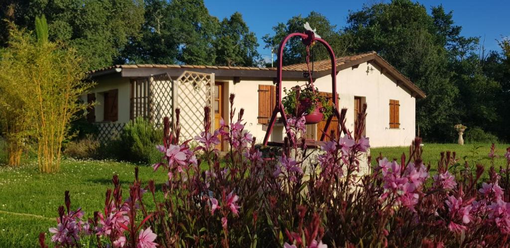 un jardin avec des fleurs roses en face d'une maison dans l'établissement Gîte Ti-Case, à Bussac-Forêt