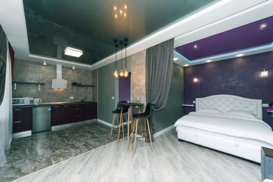 ein Schlafzimmer mit einem Bett und einem Tisch sowie eine Küche in der Unterkunft Дизайнерская Студио 10 мин метро Позняки in Kiew