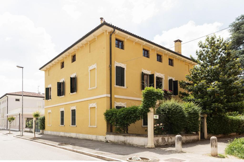 un edificio amarillo al lado de una calle en La Casa delle Zie, en Cologna Veneta