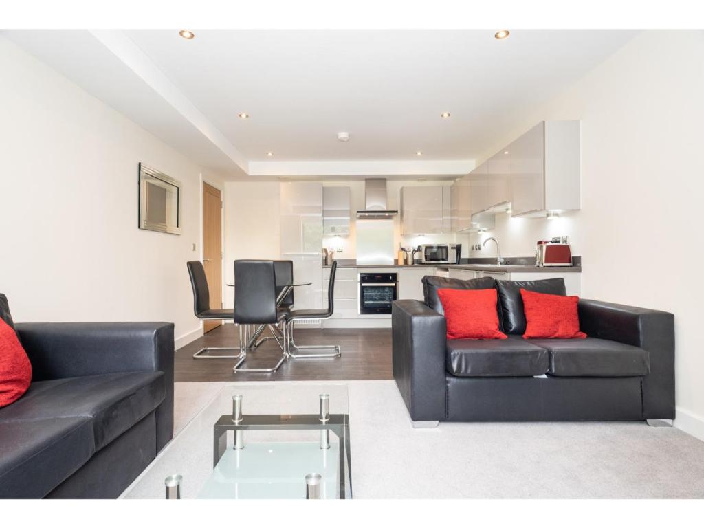 uma sala de estar com 2 sofás pretos e almofadas vermelhas em Stylish Flat Near the City Centre - Pass the Keys em York