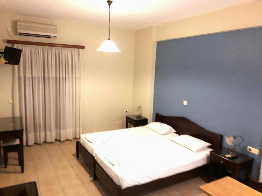 1 dormitorio con cama blanca y pared azul en Sirios, en Finikounta