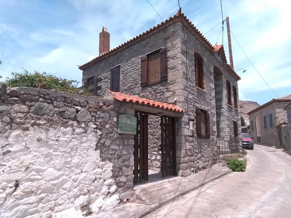 un antiguo edificio de piedra al lado de una calle en Villa Notia, en Skala Eresou