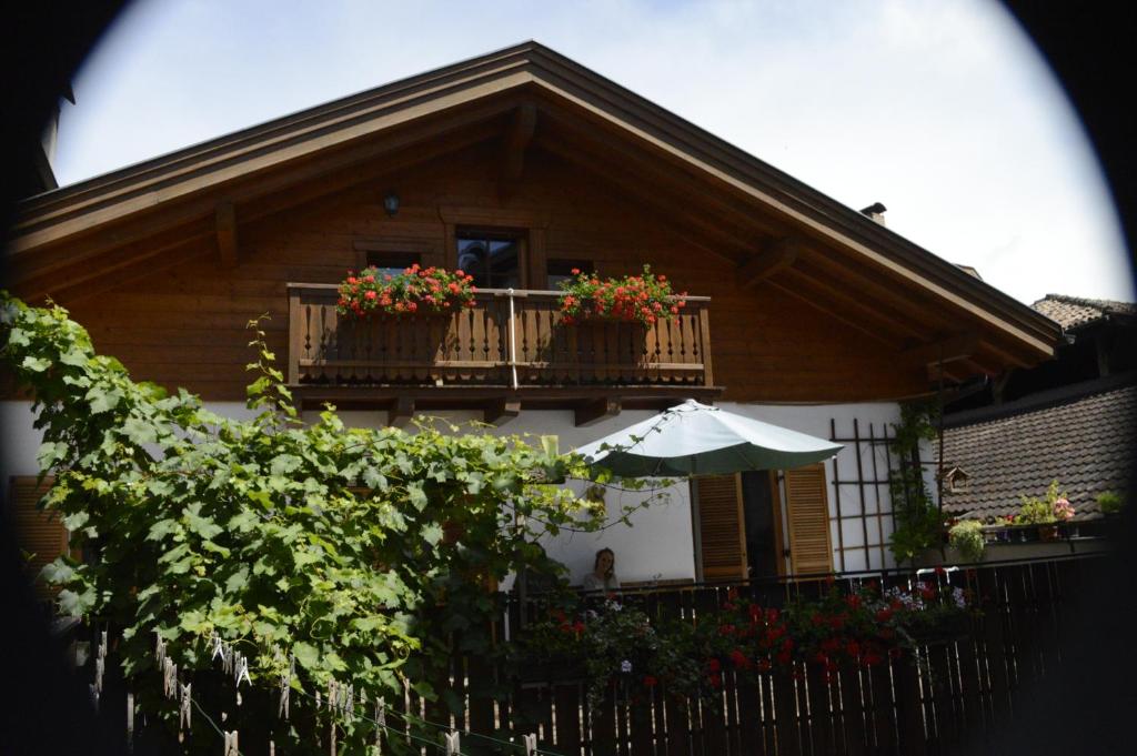 ein Haus mit einem Balkon mit Blumen und einem Sonnenschirm in der Unterkunft Hof am Brunnen in Girlan
