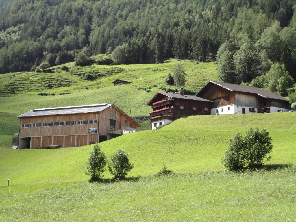 eine Gruppe von Gebäuden auf einem grünen Hügel in der Unterkunft Bauernhof Bethuber in Matrei in Osttirol