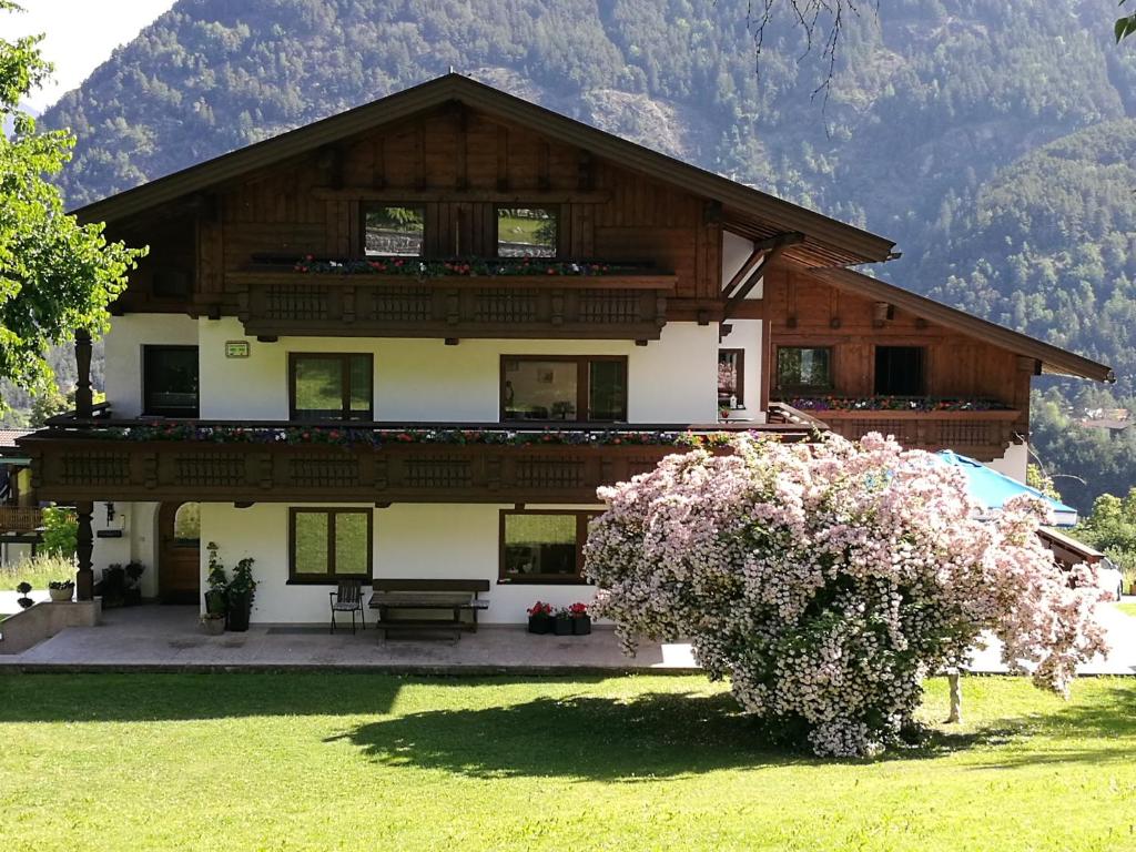 une grande maison en bois avec un arbre dans l'établissement Gästepension Wiesenheim, à Sautens