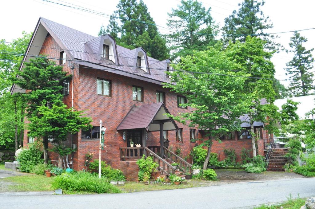 a red brick house with a gambrel roof at Pension Risuno Koya in Hakuba