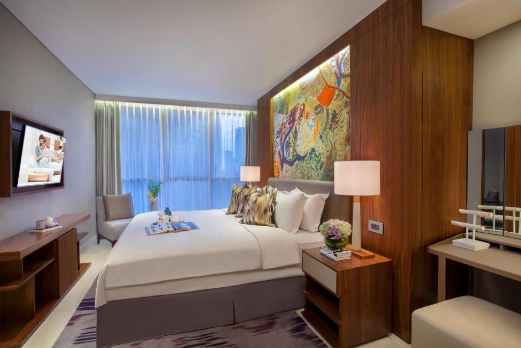 a bedroom with a large bed and a large window at Ascott Sudirman Jakarta in Jakarta