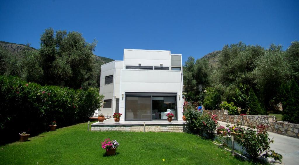 une maison blanche avec une pelouse devant elle dans l'établissement Villa Nicolas Plataria, à Plataria