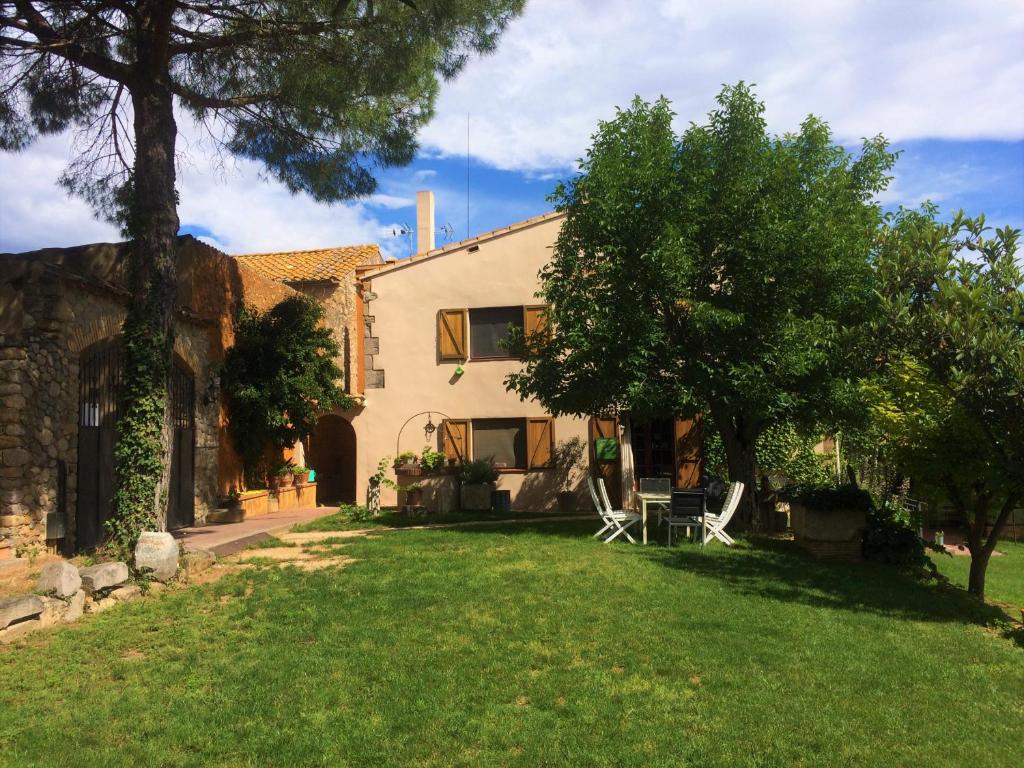 a house with a yard with two chairs and a tree at La Masia Costa Brava -Adults Only in Garrigás