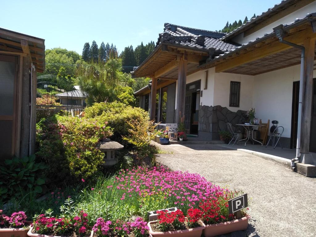 a garden with pink flowers and a house at Cocochi House in Yufuin