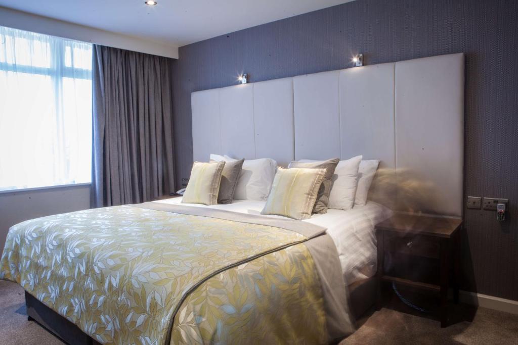 a bedroom with a large bed with white sheets and pillows at Four Seasons Hotel & Leisure Club in Monaghan