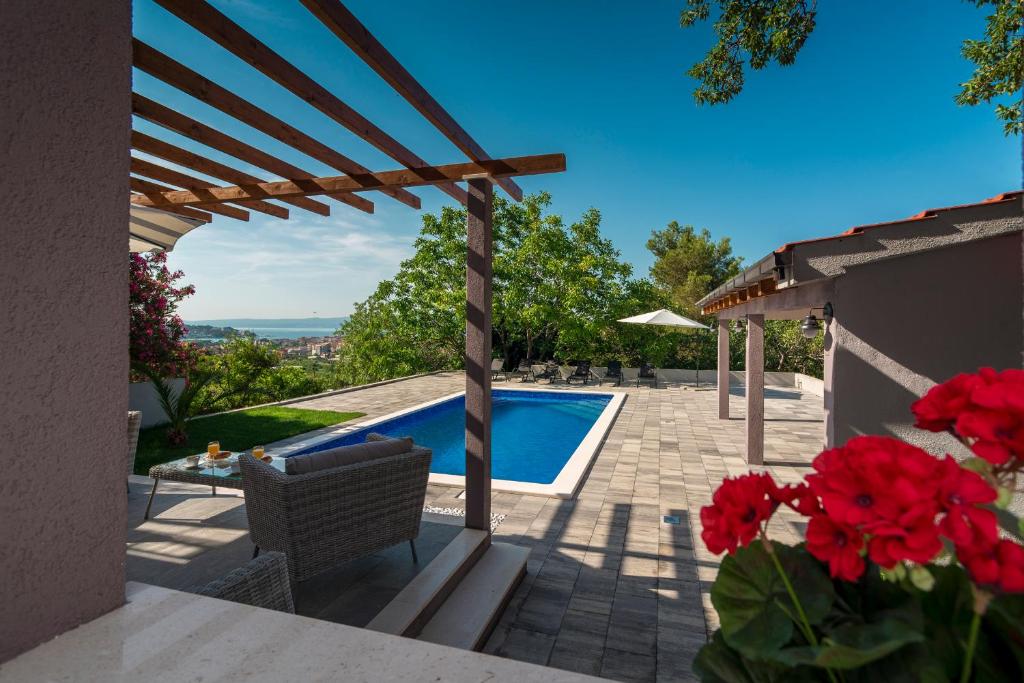 a patio with a swimming pool and red flowers at Maison Terze in Split