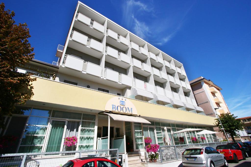 Hotel Boom في ريميني: مبنى فندق فيه سيارات تقف امامه