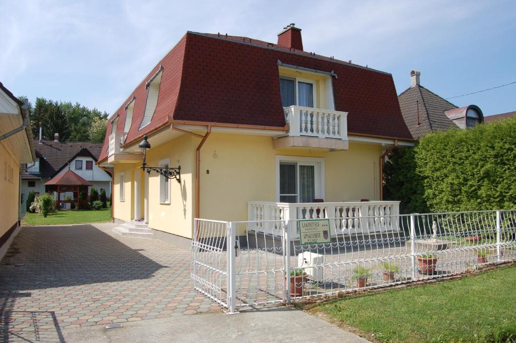 une maison avec une clôture blanche devant elle dans l'établissement Apartmanház Cédrus 8 Zalakaros, à Zalakaros
